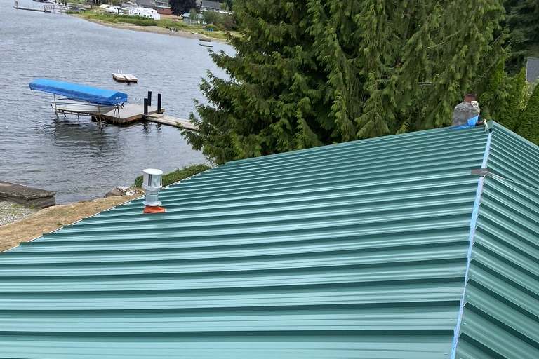 New green standing-seam metal roof on a lakeside home in the Spokane area