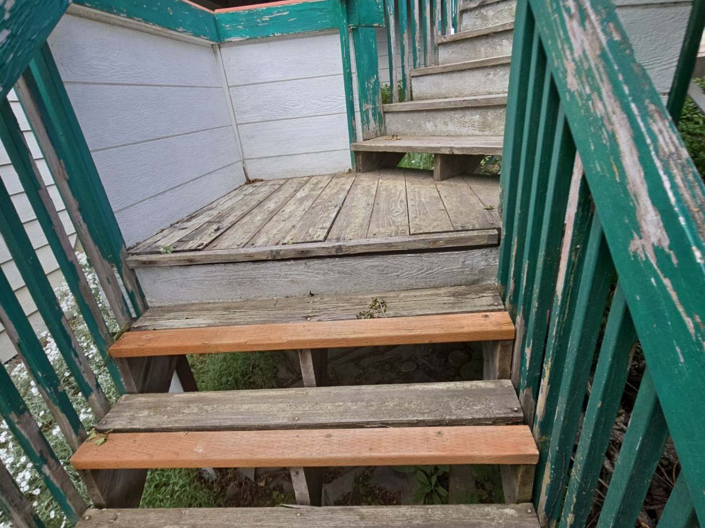 A weathered deck with gray, sun-bleached boards and peeling railing paint — the before state on an exterior wood staining and sealing job.